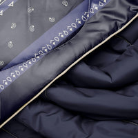 Close-up detail of navy puffy blanket showing paisley bandana print border and cream piping edge