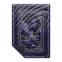 Quilted puffy blanket in navy blue bandana print with mountain camping scene graphic, flat lay view