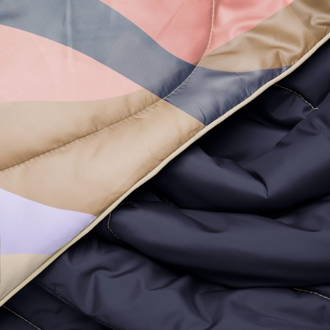 Folded puffy blanket with geometric color-blocked pattern in navy, coral, beige and purple sections