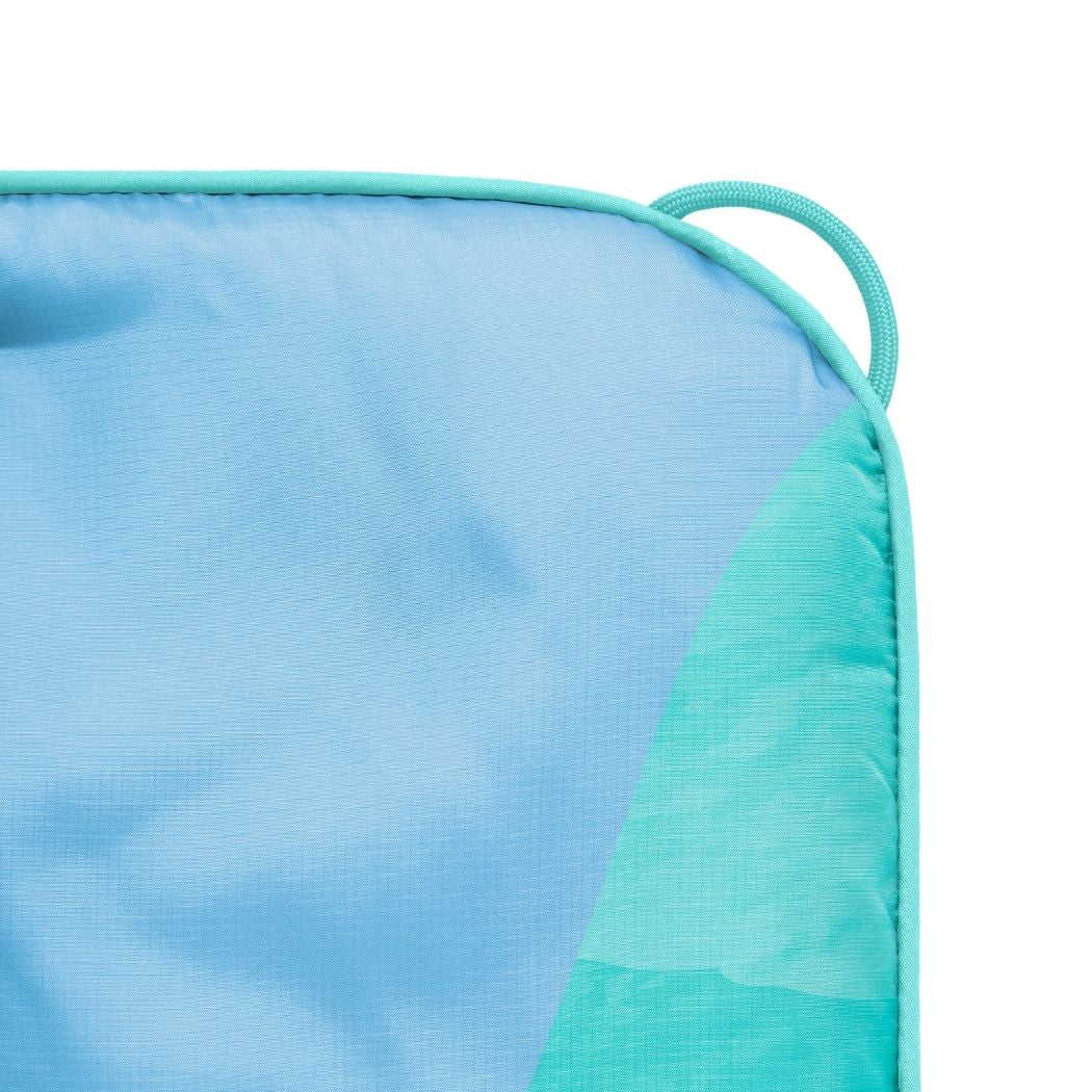 Corner detail of puffy blanket with blue to teal gradient pattern and fabric loop handle