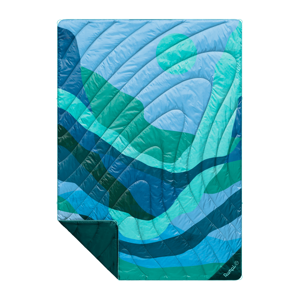 Quilted puffy blanket with blue and teal wave pattern, folded to show corner detail