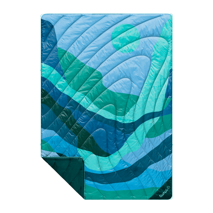 Quilted puffy blanket with blue and teal wave pattern, folded to show corner detail