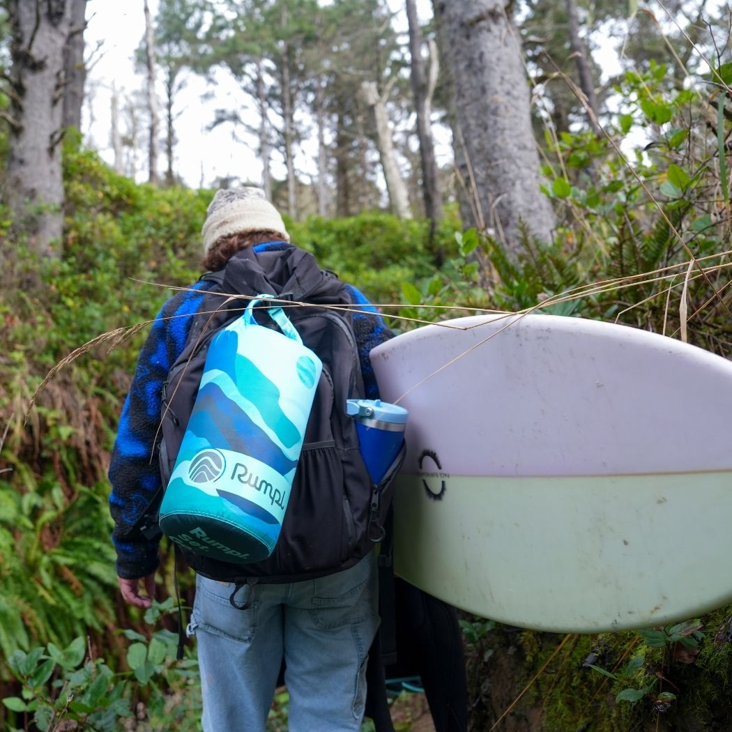 Person wearing backpack with blue geometric patterned puffy blanket attached in forest setting