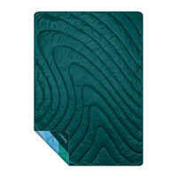 Teal quilted blanket with curved wave-like stitching pattern, folded corner showing lighter blue interior