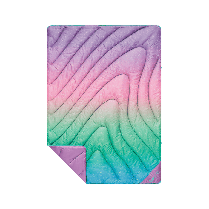 Quilted puffer blanket with rainbow ombre gradient pattern, corner folded back showing solid purple reverse side