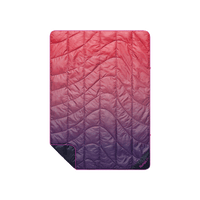 Quilted puffy travel blanket with pink-to-purple ombre gradient and wave-pattern stitching, flat lay view