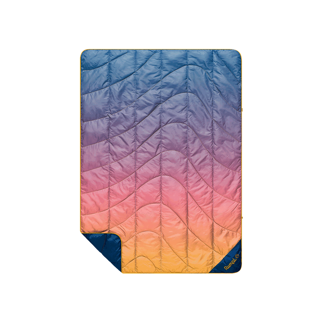 Quilted puffy blanket with sunset gradient ombre pattern, blue to orange, with navy reverse side