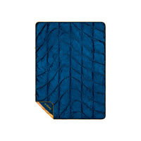 Quilted travel blanket in deep navy blue with gold trim, corner folded to reveal reverse side