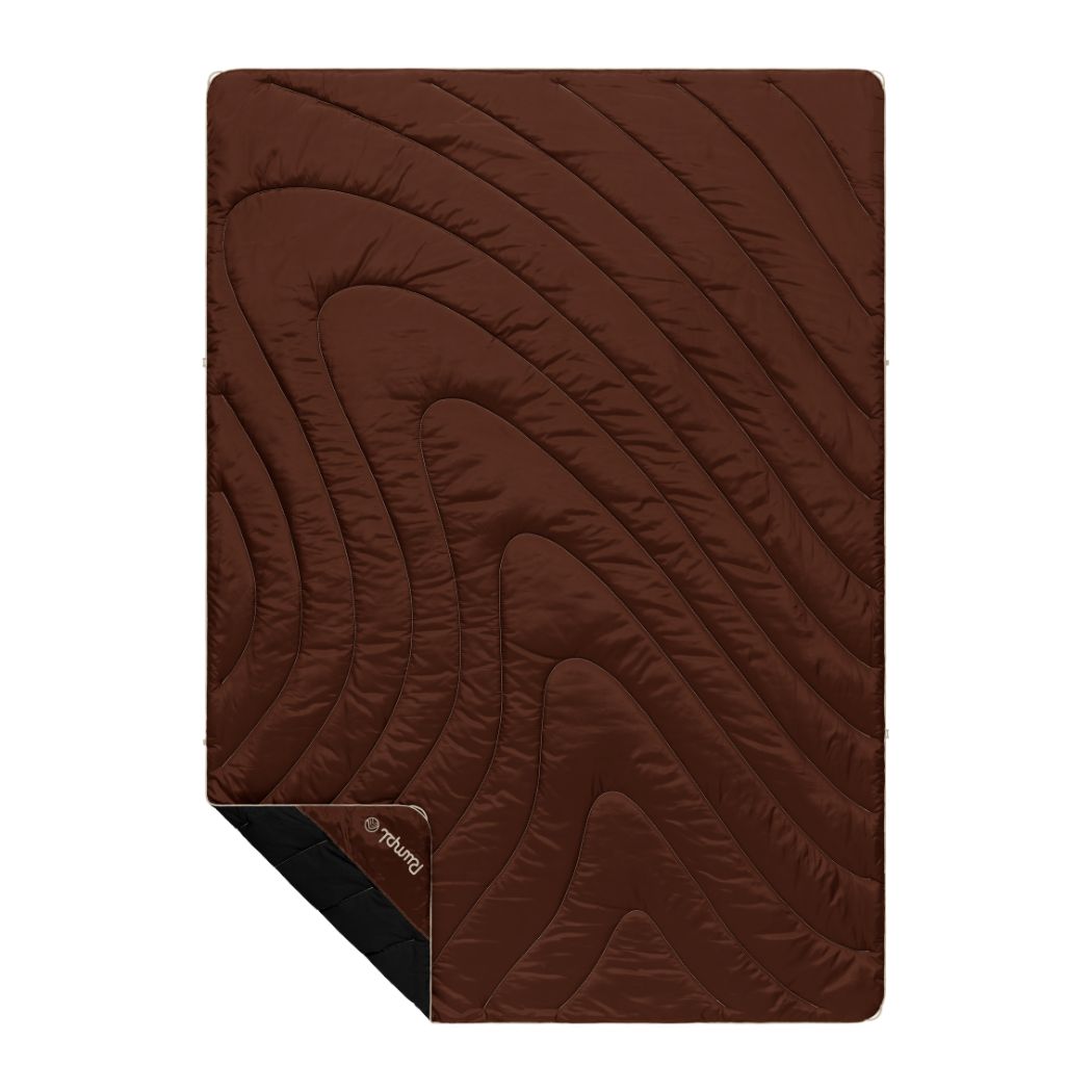 Brown quilted camping blanket with curved stitching pattern and black reverse side visible at corner
