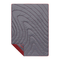 Gray quilted puffy blanket with curved wave pattern and red trim, flat lay view