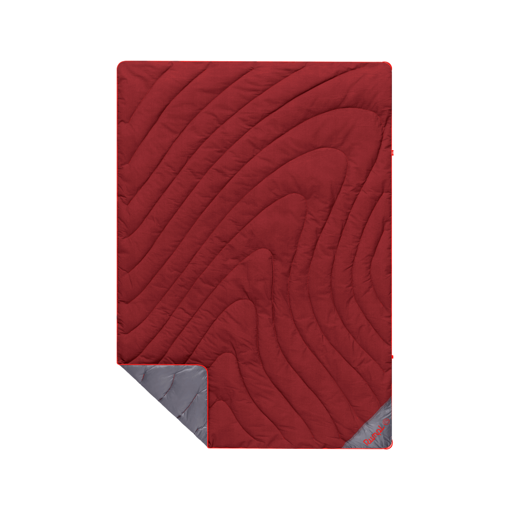 Red quilted puffy blanket with topographic swirl pattern, corner folded to reveal gray underside