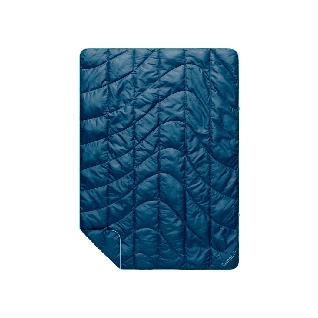 Quilted puffy travel blanket in deep teal with wave pattern stitching and folded corner