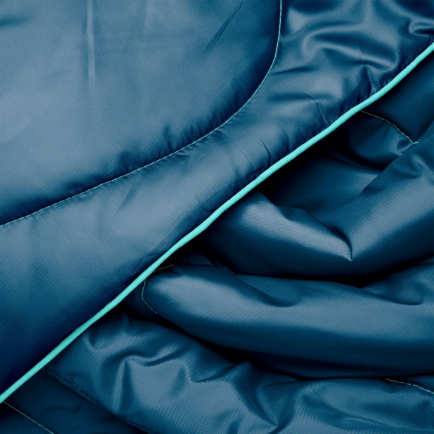 Close-up of a quilted puffy travel blanket in deep teal with mint accent trim detail