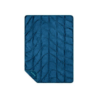 Deep blue quilted travel blanket with vertical stitching pattern and teal trim, flat lay view