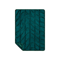 Quilted puffy travel blanket in deep teal with green trim, flat lay view showing stitched pattern