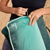 Person holding folded camping mat with gradient green design and zipper closure