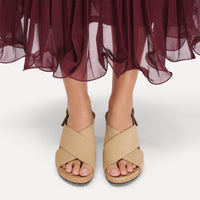 Light tan leather sandals with crossed straps and cork footbed worn with flowing burgundy skirt