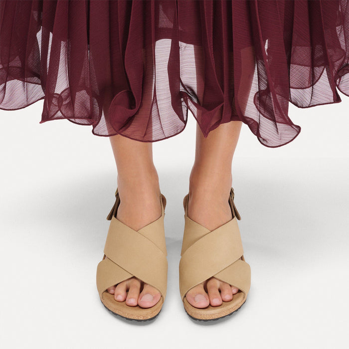 Light tan leather sandals with crossed straps and cork footbed worn with flowing burgundy skirt