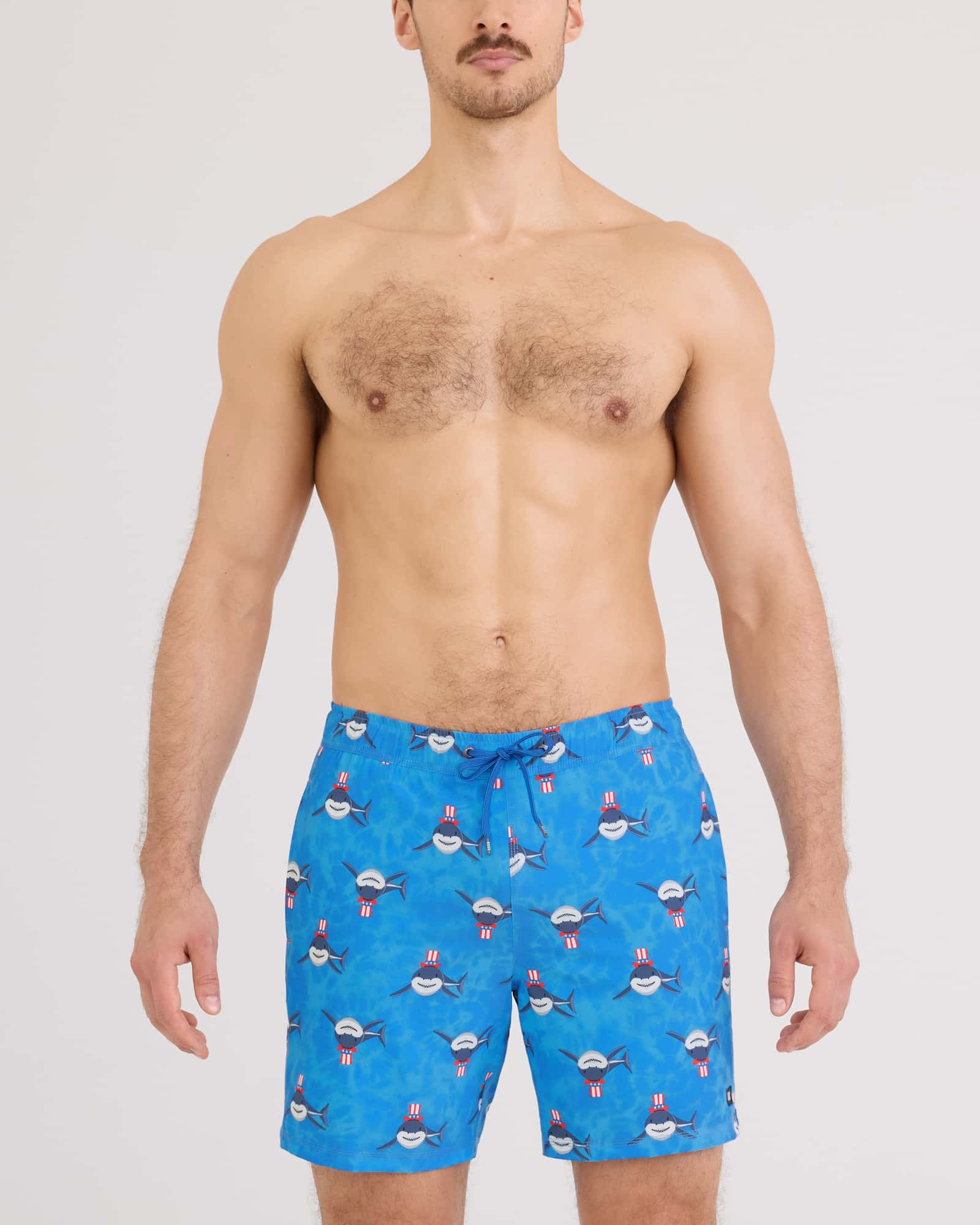 Men's blue swim trunks with patriotic shark pattern, drawstring waist, front view on model