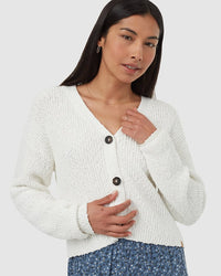 Woman wearing cream knit cardigan with two dark buttons and V-neck styling