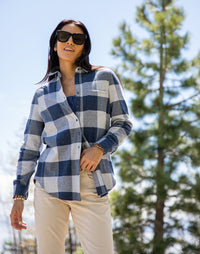 Women's plaid flannel button-up shirt in navy and white check, worn open over a top