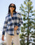Women's plaid flannel button-up shirt in navy and white check, worn open over a top