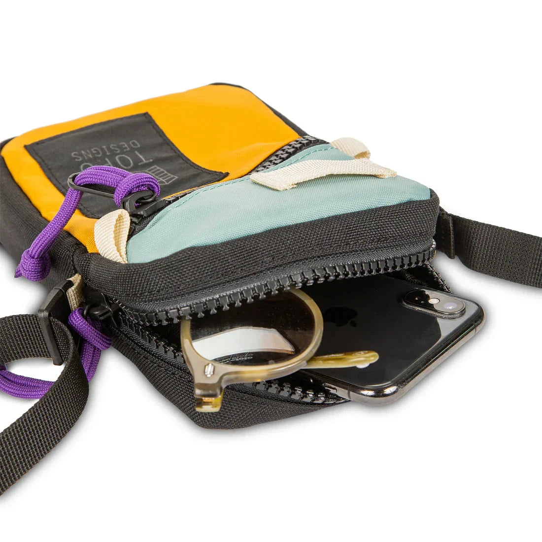 Small crossbody bag with zippered compartments open showing phone and accessories inside