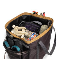 Open gear bag showing packed climbing equipment including harnesses and rope with external pockets