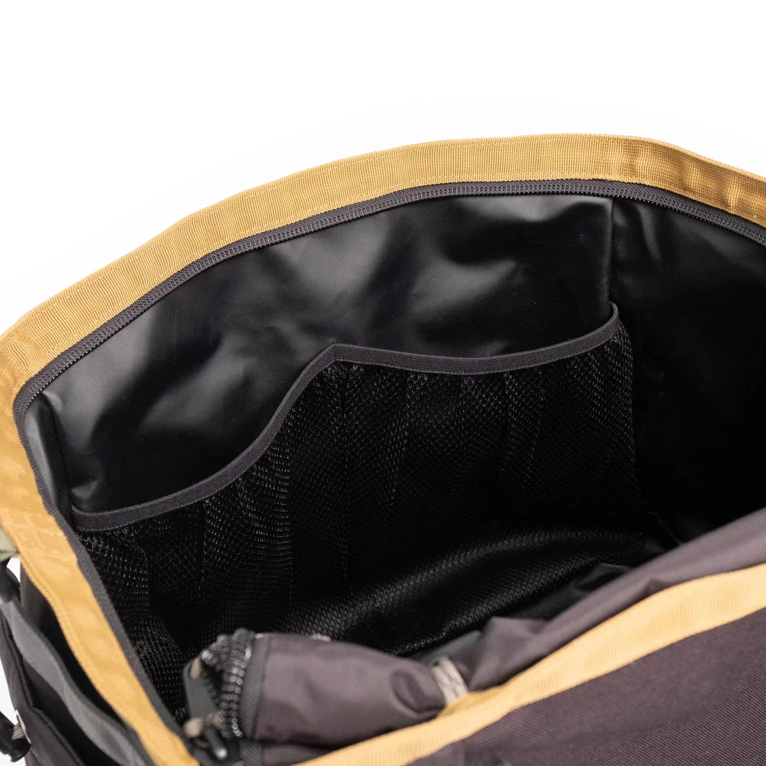 Open gear bag showing interior mesh pockets and black lining, mustard yellow exterior