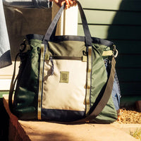 Multi-colored duffel bag with handles and shoulder strap, featuring front pocket and drawstring closure