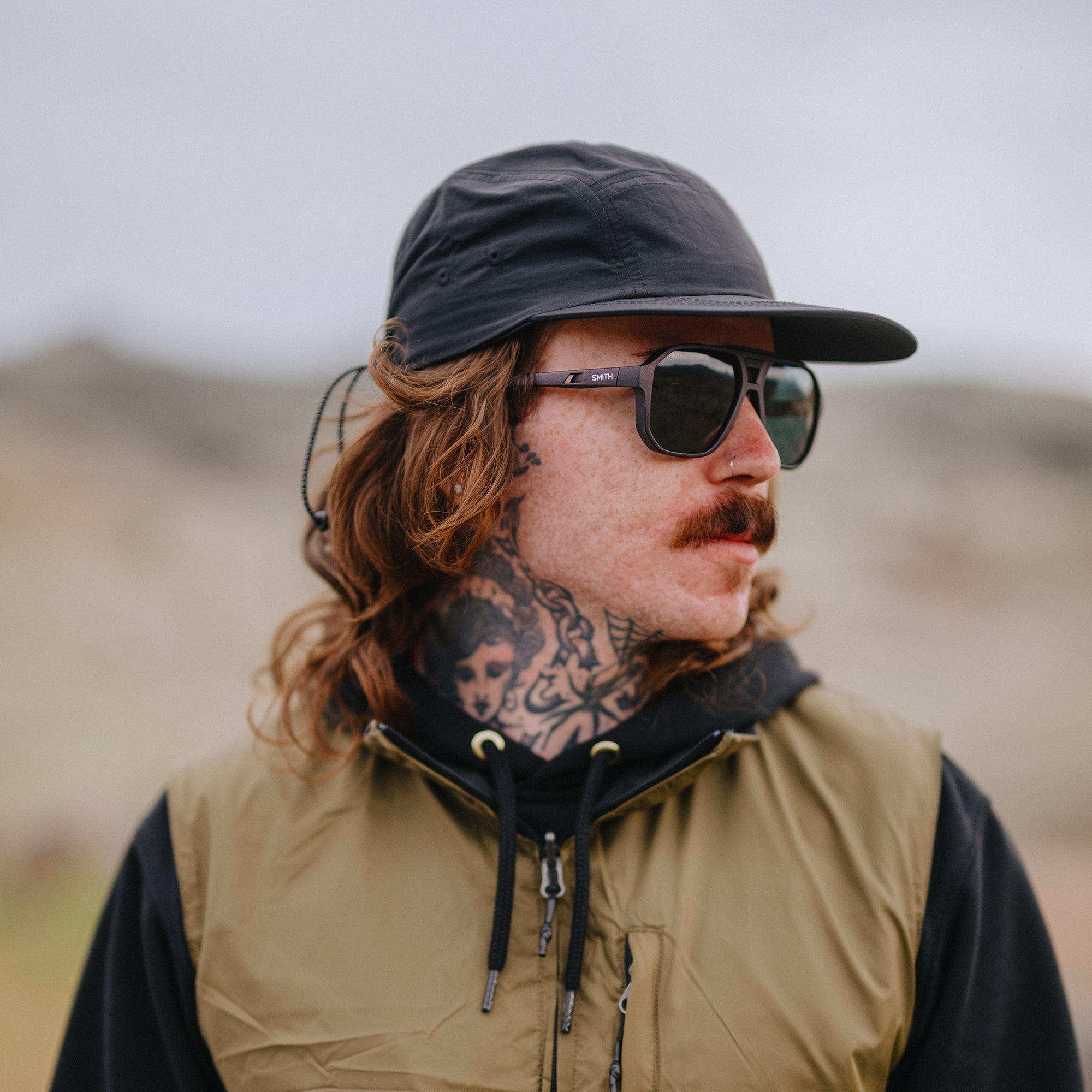 Square-framed sunglasses with dark lenses worn by person in outdoor lifestyle setting