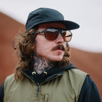 Person wearing square aviator-style sunglasses with dark frames and brown photochromic lenses, lifestyle shot