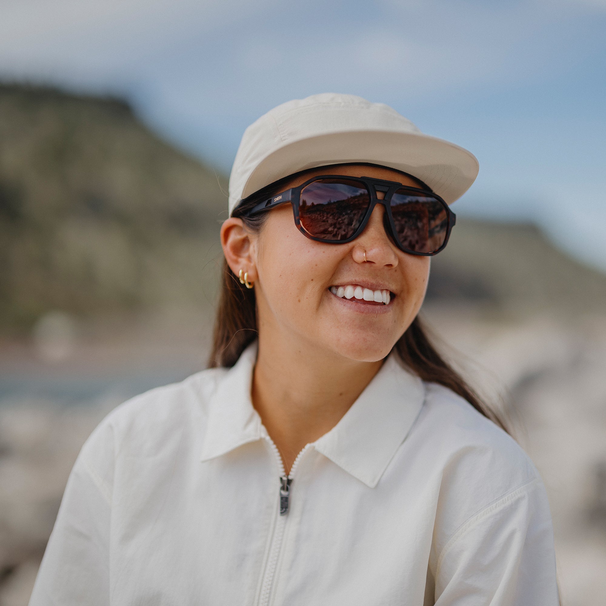 Woman wearing aviator-style sunglasses with tortoise frames and dark lenses outdoors