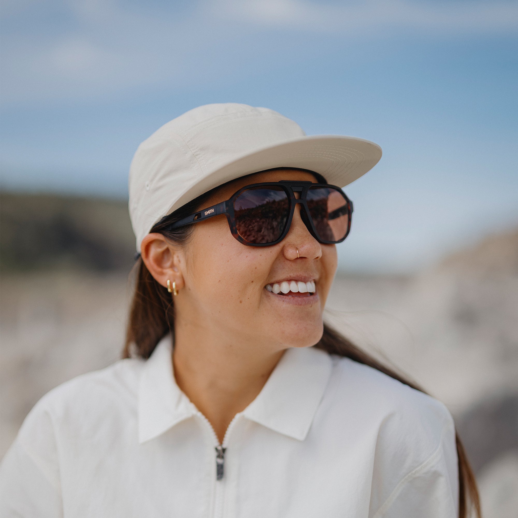 Woman wearing large square aviator sunglasses with tortoise frames and brown lenses outdoors