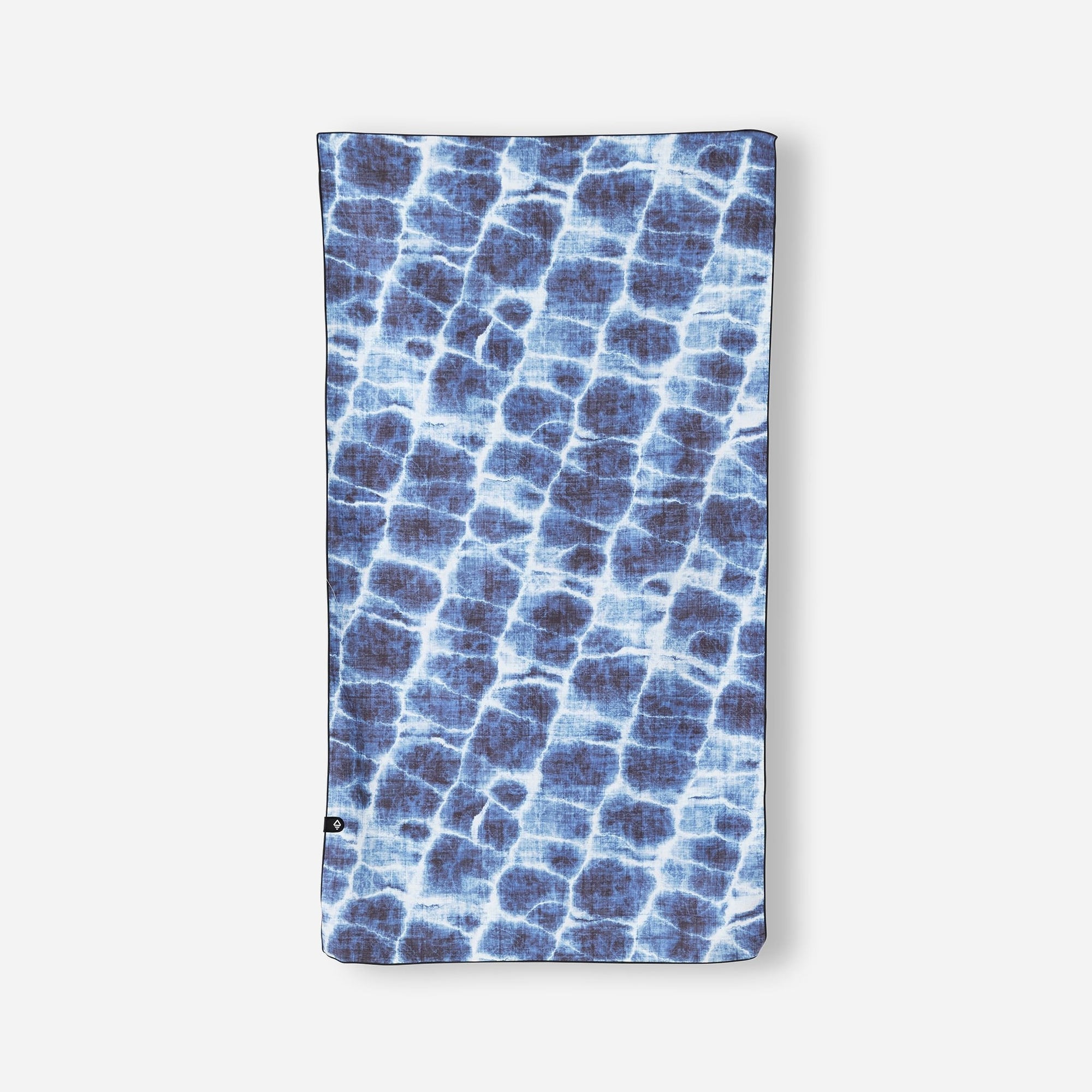 Blue patterned lightweight towel with water ripple design laid flat against white background