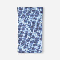 Blue patterned lightweight towel with water ripple design laid flat against white background