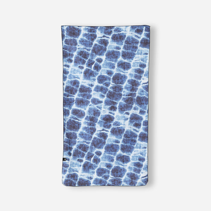 Blue patterned lightweight towel with water ripple design laid flat against white background