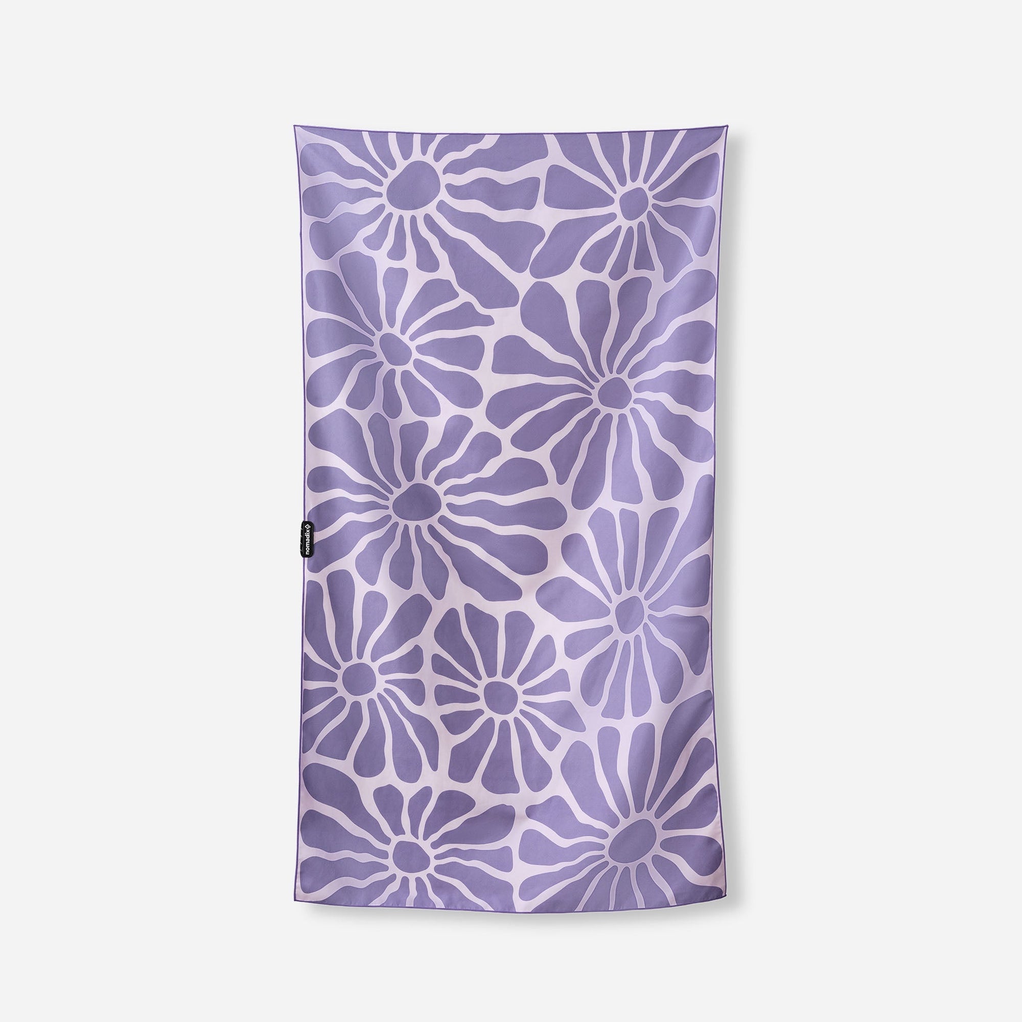 Purple towel with white daisy flower pattern laid flat on white background