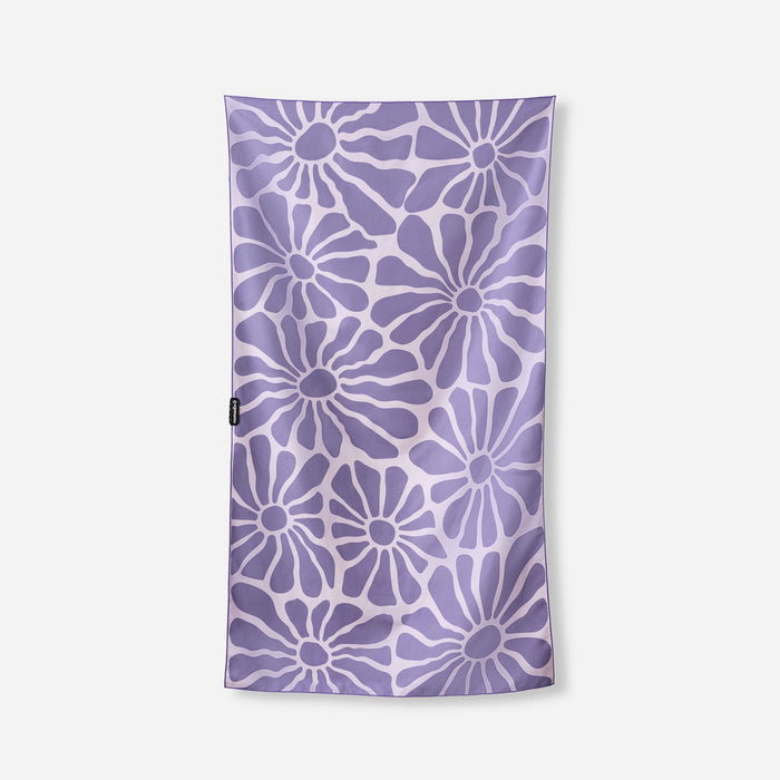 Purple towel with white daisy flower pattern laid flat on white background