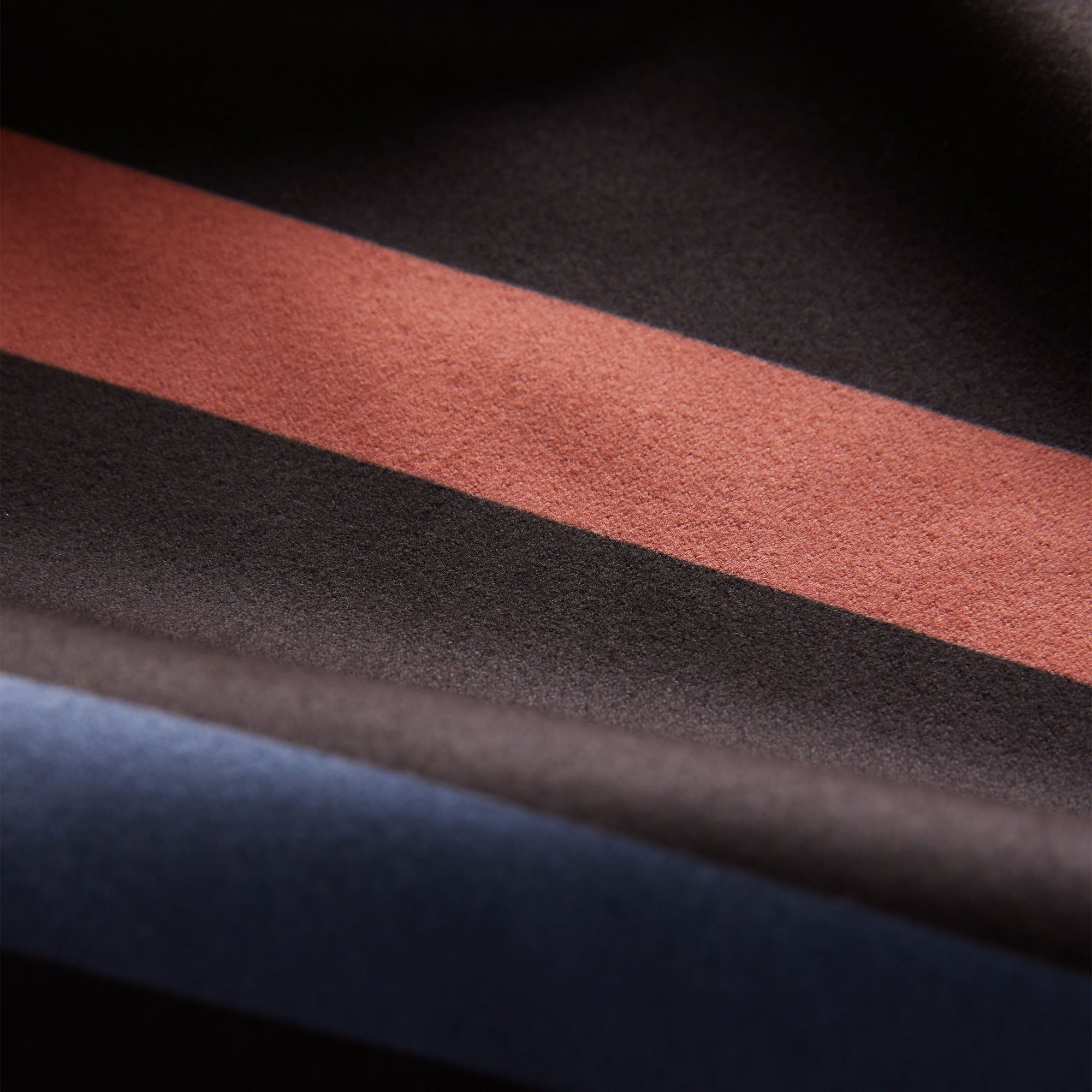 Folded towel showing striped pattern with coral, black and navy blue bands