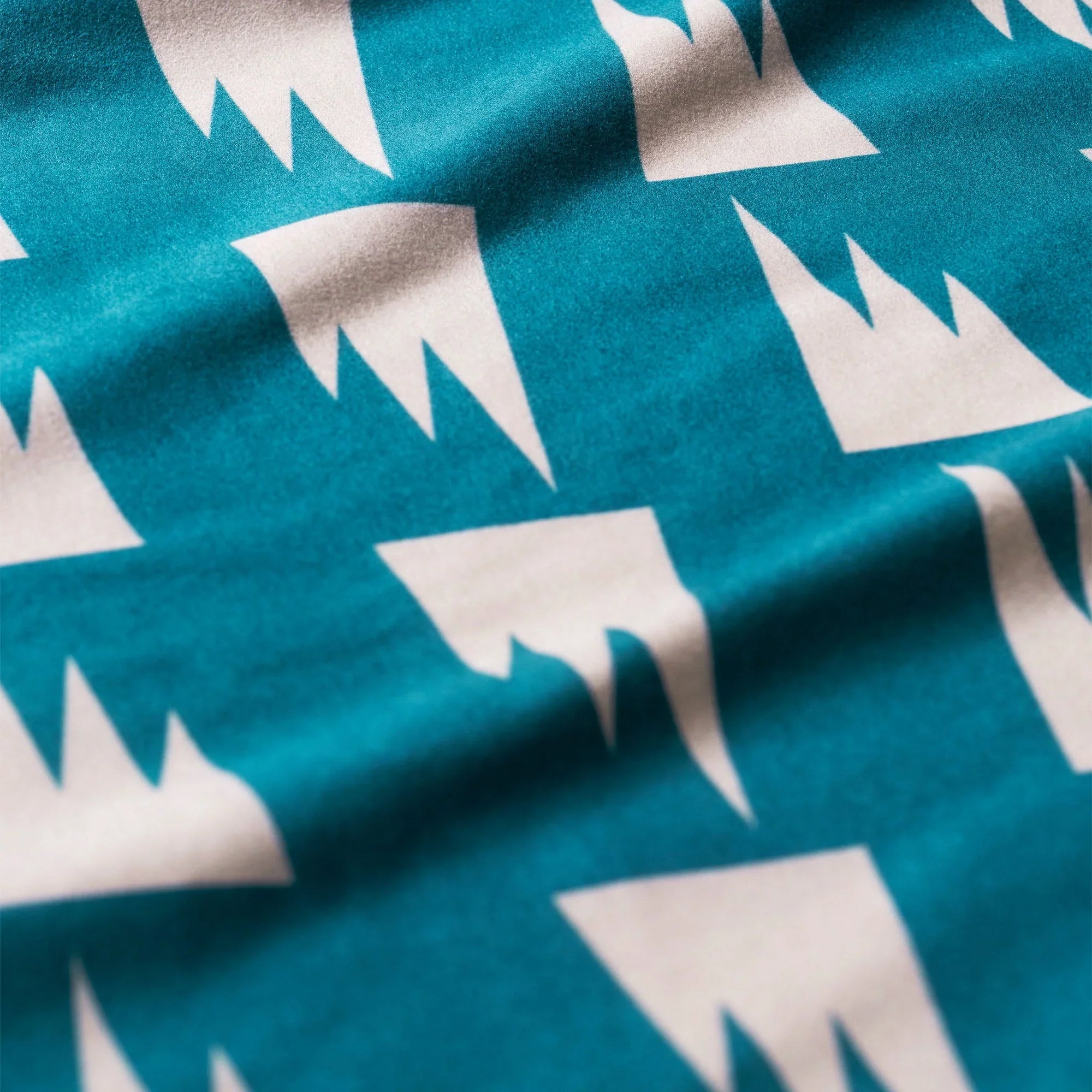 Folded ultralight towel with teal background and white crown pattern design