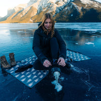 Blue patterned towel laid flat on frozen lake surface with person sitting on edge