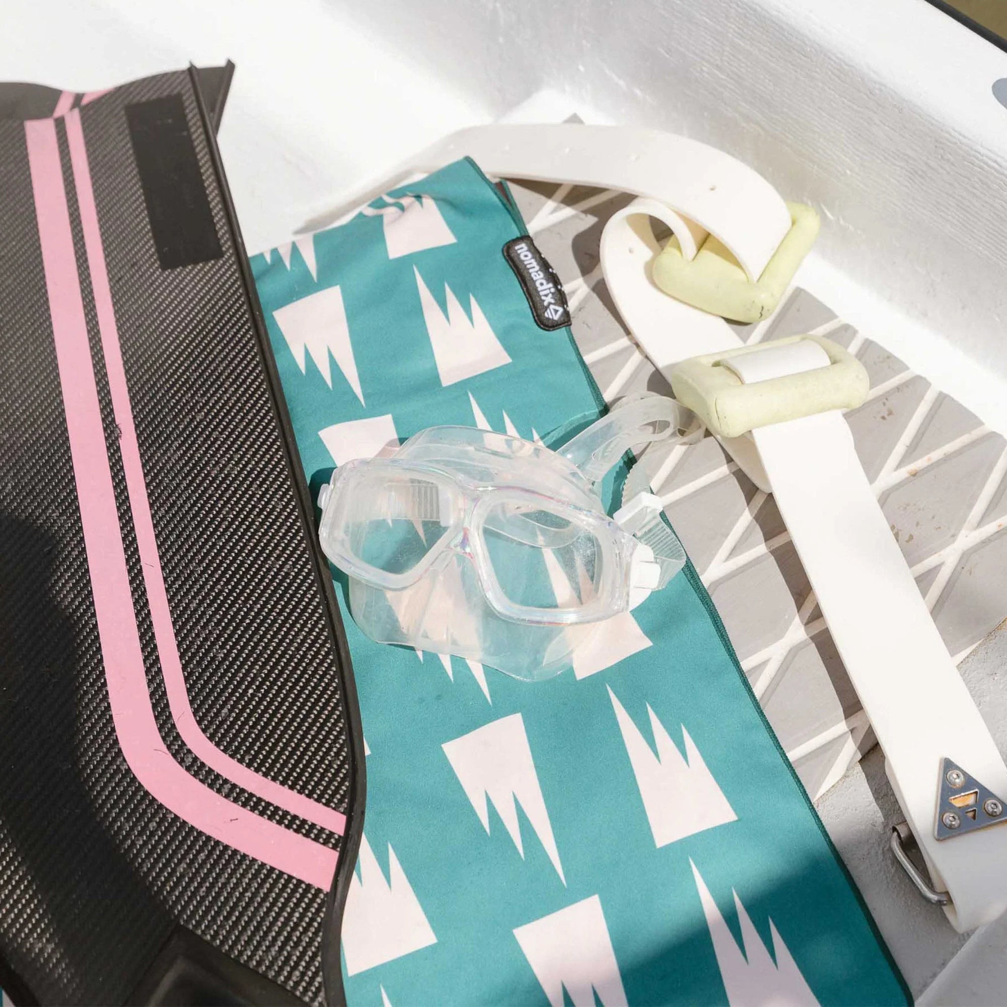 Turquoise ultralight towel with white geometric pattern, folded with clear storage pouch