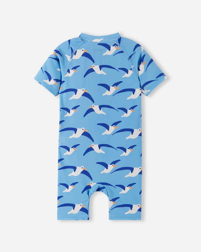 Baby sunsuit back view, short-sleeve one-piece with all-over seagull print on blue background