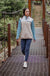 Woman walking on a suspension bridge wearing a color-block fleece pullover with teal sleeves and beige body