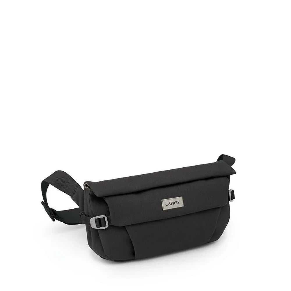 Small black crossbody hip bag with flap closure, adjustable strap, and metal logo badge